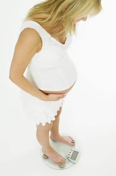 Embarazada mujer de pie en la escala de peso —  Fotos de Stock