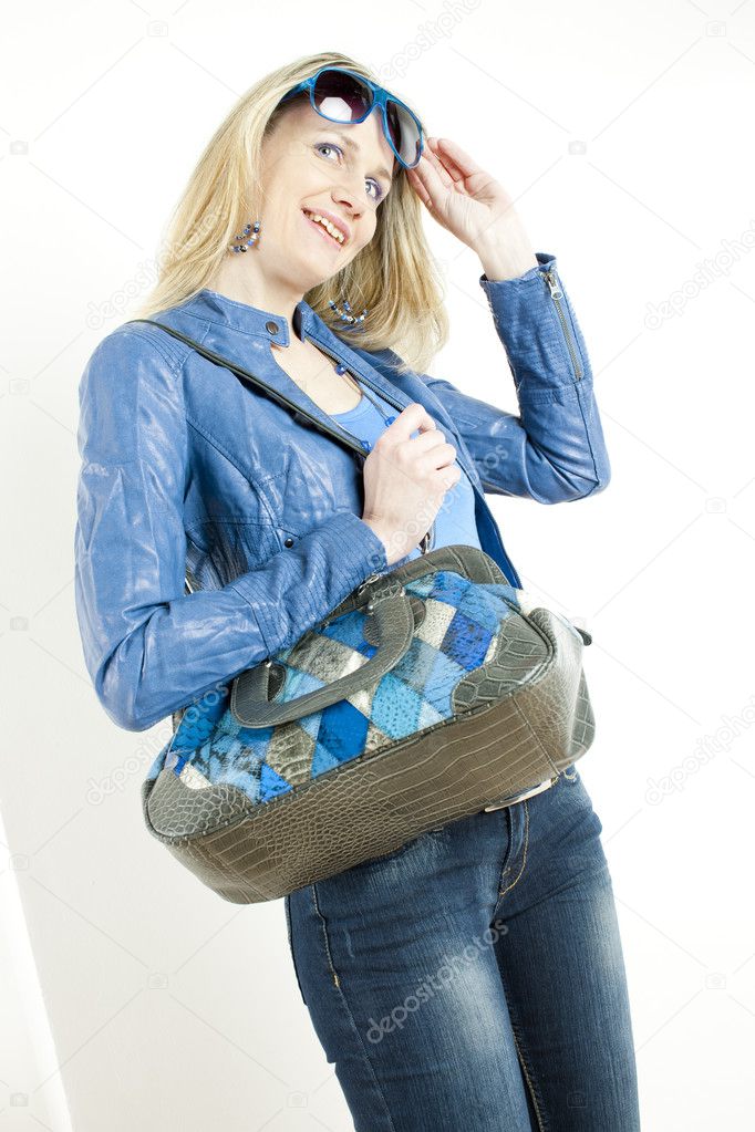 Portrait of standing woman wearing blue clothes with handbag