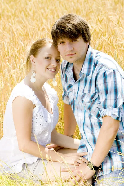 Unga par som sitter på sädesfält — Stockfoto