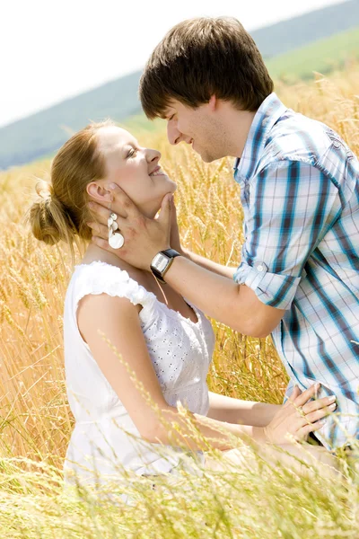 若いカップルが穀物畑に座っている — ストック写真