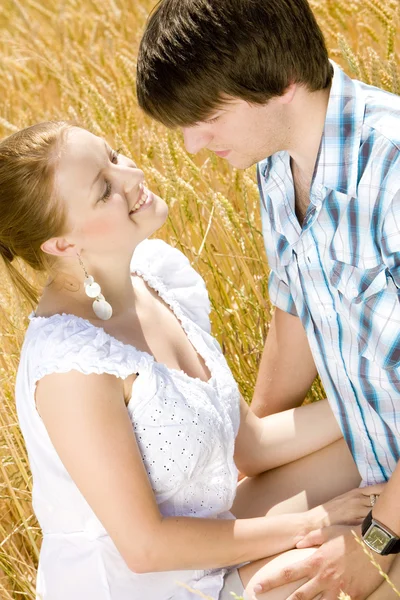Jovem casal sentado no campo de grãos — Fotografia de Stock