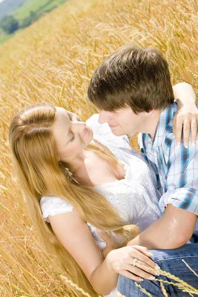 Jovem casal sentado no campo de grãos — Fotografia de Stock