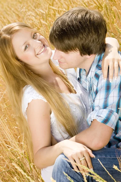 Νεαρό ζευγάρι κάθεται στο χωράφι με τα σιτηρά — Φωτογραφία Αρχείου