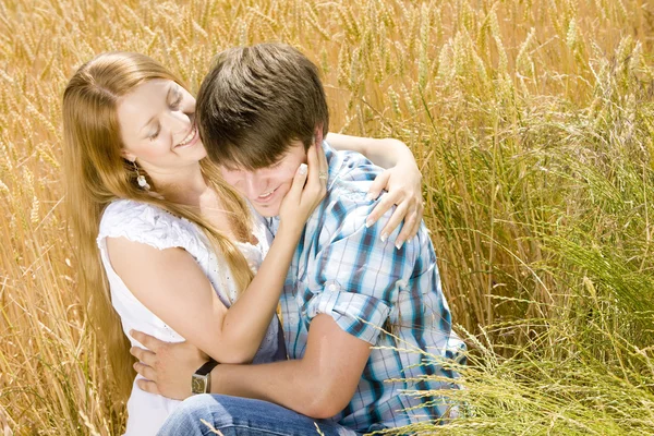 Молода пара сидить у зерновому полі — стокове фото