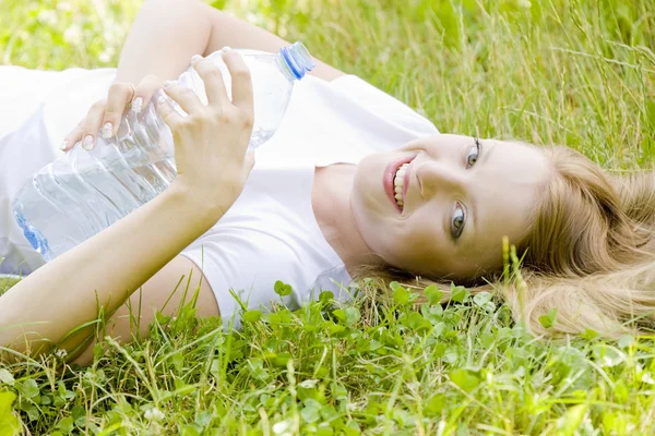 Kobieta leżący z butelka wody — Zdjęcie stockowe