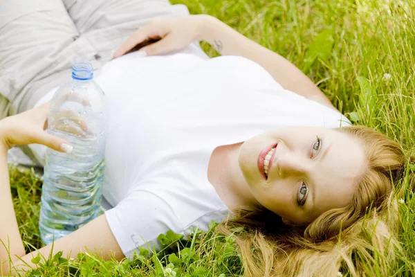Mulher deitada com garrafa de água — Fotografia de Stock