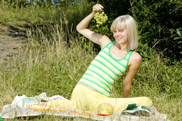 Женщина с виноградом на пикнике — стоковое фото