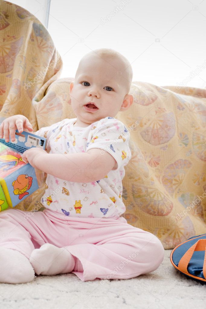 Baby girl with toys sitting on the carpet