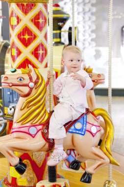 Sitting toddler on carousel clipart