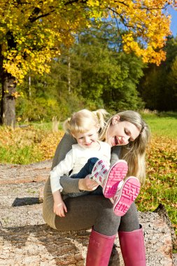 Mother with her little daughter in autumnal nature clipart