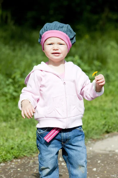 Litlle dívka na procházce držící květ — Stock fotografie
