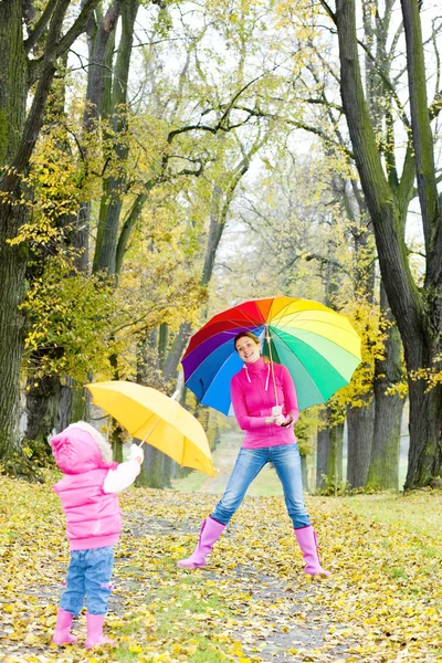Moeder en haar dochter met paraplu's in herfst steegje — Stockfoto