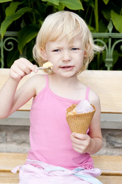 Liten jente med iskrem sittende på benken – stockfoto