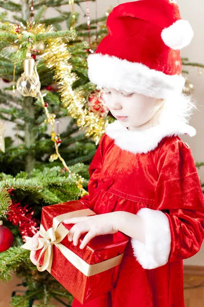 Kleines Mädchen als Weihnachtsmann mit Weihnachtsgeschenk — Stockfoto