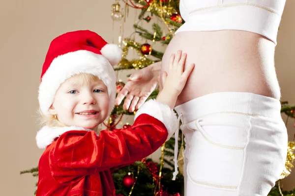 Porträt eines kleinen Mädchens und ihrer schwangeren Mutter zu Weihnachten — Stockfoto