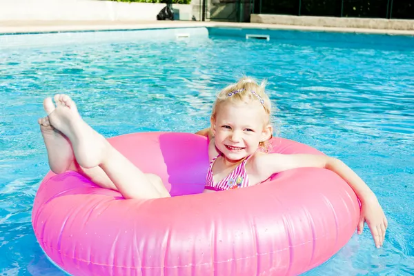 Маленькая девочка с резиновым кольцом в бассейне — стоковое фото