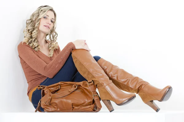 ハンドバッグとファッショナブルな茶色のブーツを着て座っている女性 — ストック写真