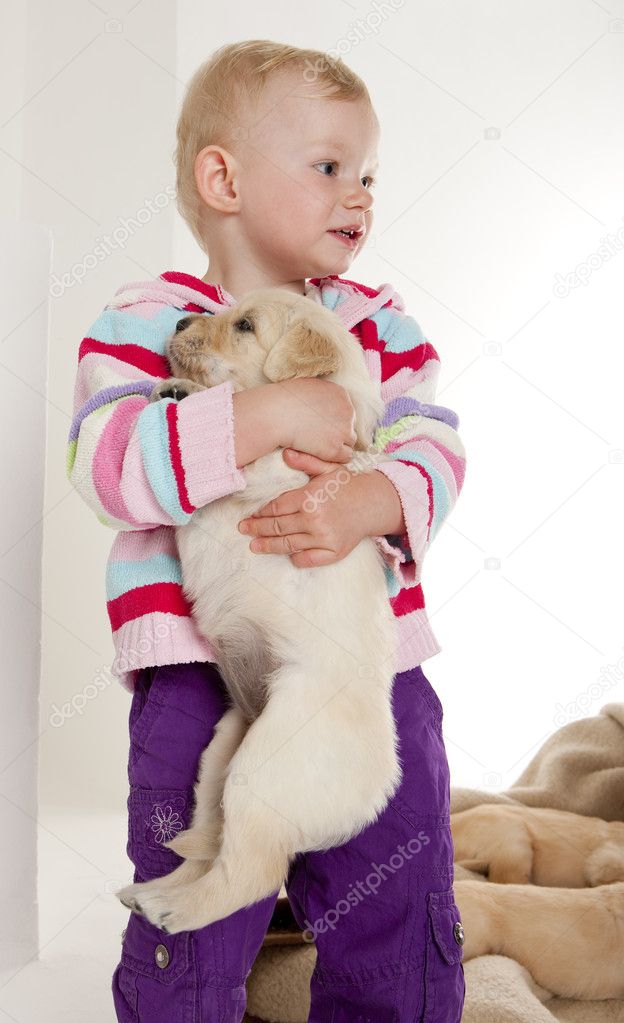 Little girl playing with puppy of golden retriever