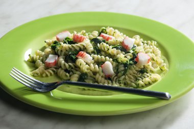 Pasta fussili with crab sticks and spinach clipart