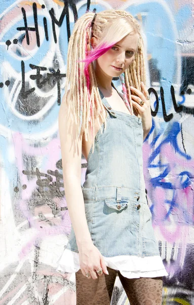 Mujer joven de pie en la pared de graffitti — Foto de Stock