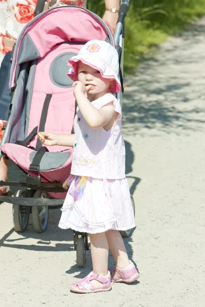 Little girl on walk with a pram — Stockfoto