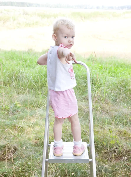 Malá holčička, stojící na žebříku — Stock fotografie