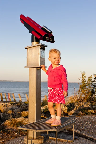 Standing little girl by telescope — Stock Photo, Image