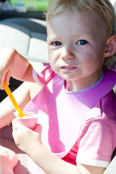 Портрет маленькой девочки, которая ест йогурт — стоковое фото