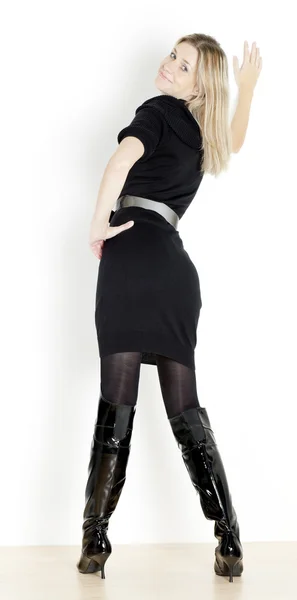 Standing woman wearing black dress and fashionable boots — Stock Photo, Image