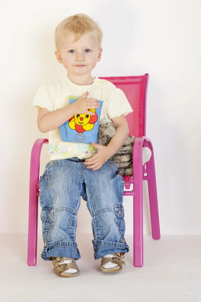 Тодлер, сидящий на стуле с игрушками — стоковое фото