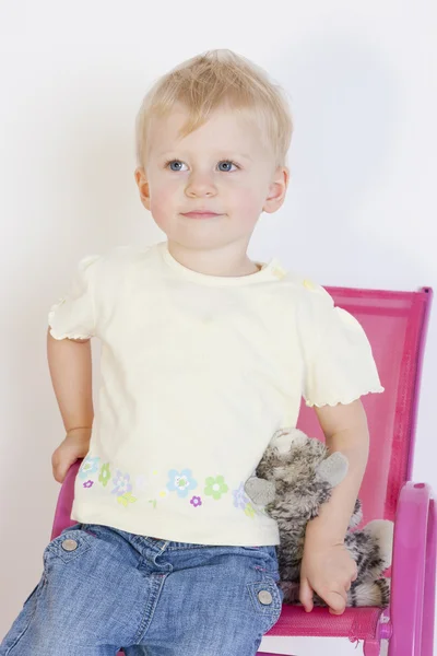 Porträt eines Kleinkindes, das mit einem Spielzeug auf einem Stuhl sitzt — Stockfoto