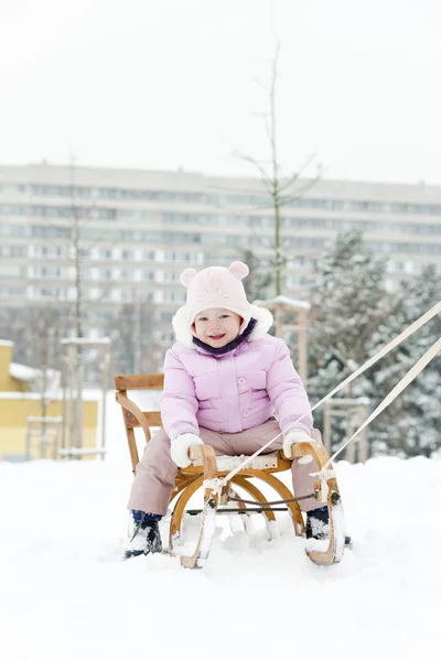 Маленькая девочка катается на санках в снегу — стоковое фото