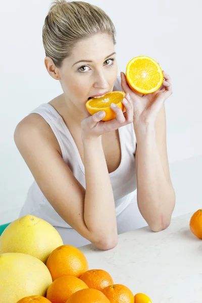 Портрет молодой женщины, которая ест апельсин — стоковое фото