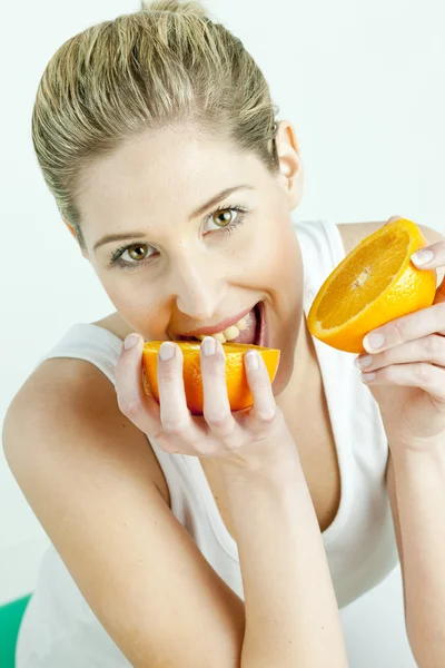 Portret van een jonge vrouw eten oranje — Stockfoto