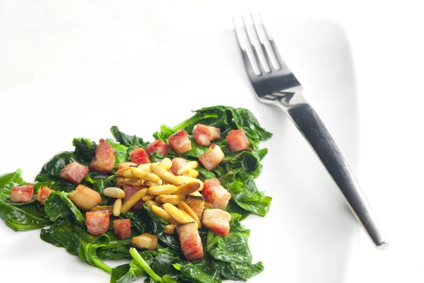 Fried spinach with bacon and pine nuts — Stock Photo, Image