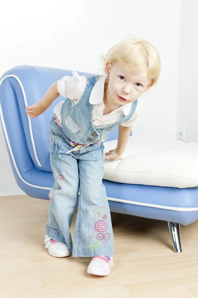 Little girl standing by sofa — Stock Photo, Image