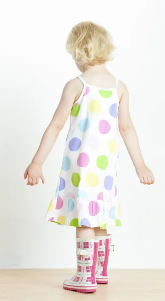 Liten flicka klädd i klänning och gummi stövlar — Stockfoto