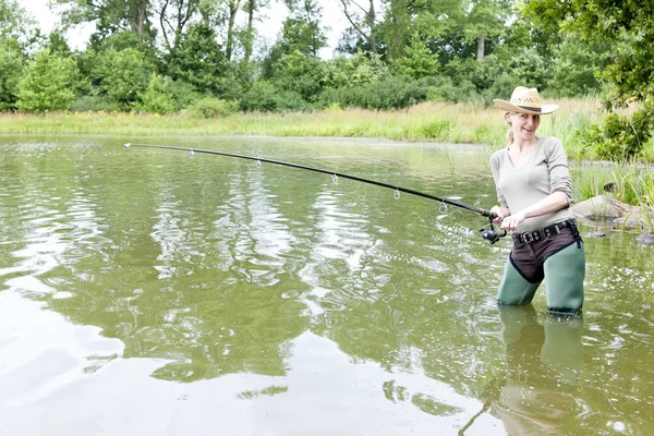 Женщина рыбачит в пруду — стоковое фото
