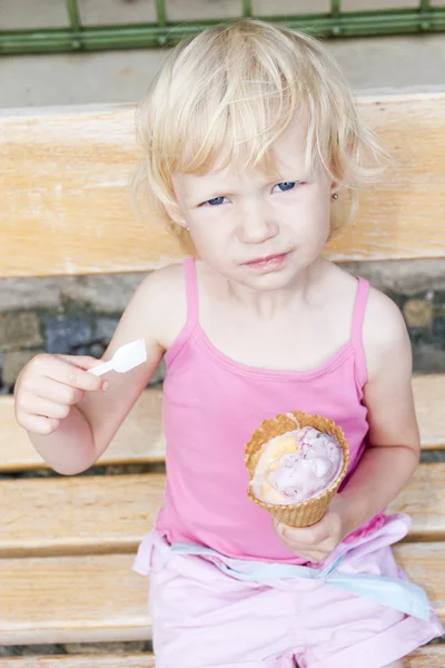 Kleines Mädchen mit Eis auf Bank sitzend — Stockfoto