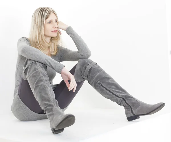 Sitzende Frau in modischen grauen Stiefeln — Stockfoto