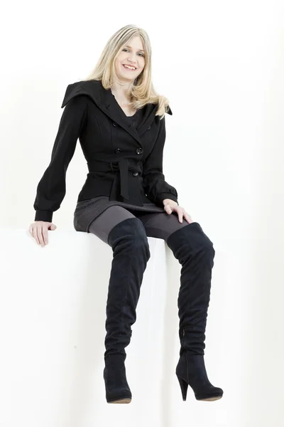 Femme assise portant des bottes noires à la mode — Photo