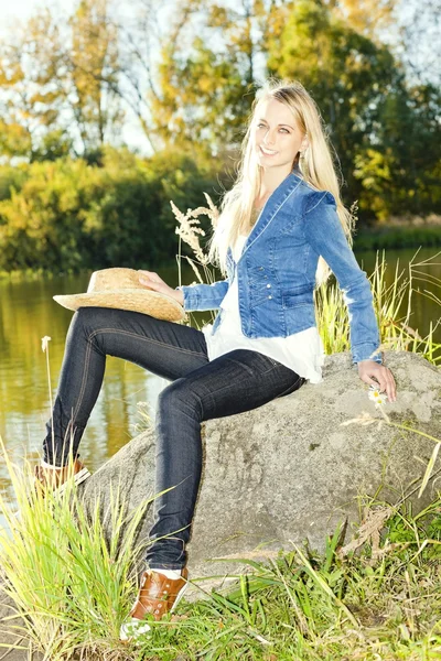 Jeune femme assise sur la pierre à l'étang — Photo