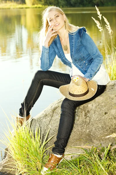 Taş gölet üzerinde oturan genç kadın — Stok fotoğraf