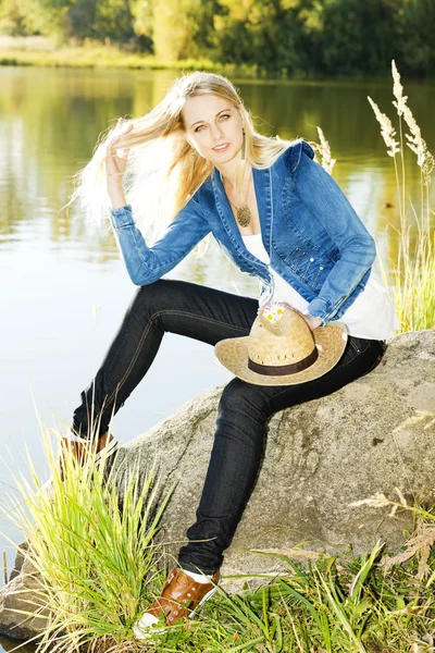 年轻女子坐在石头上池塘 — 图库照片