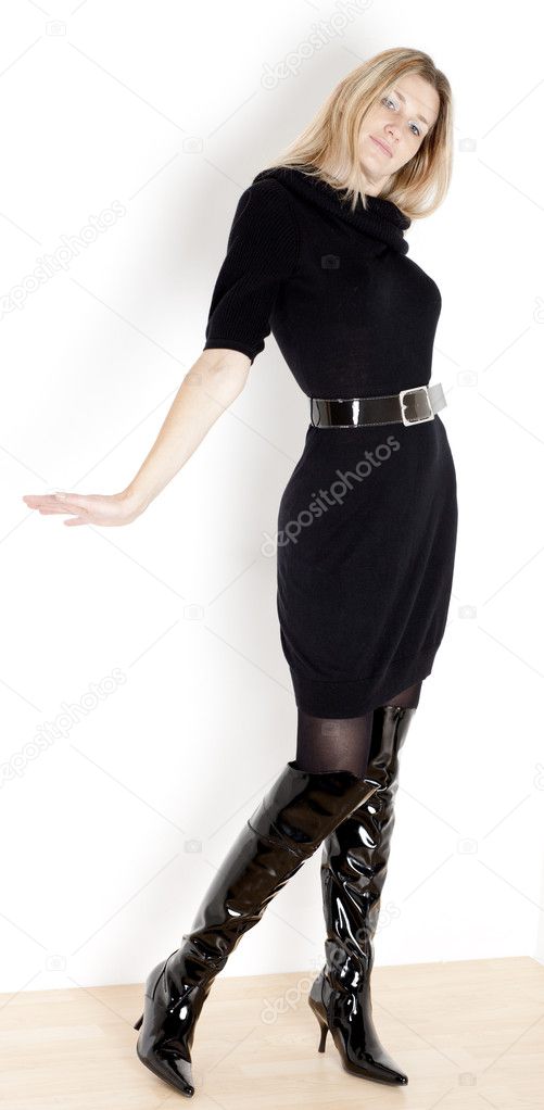Standing woman wearing black dress and fashionable boots