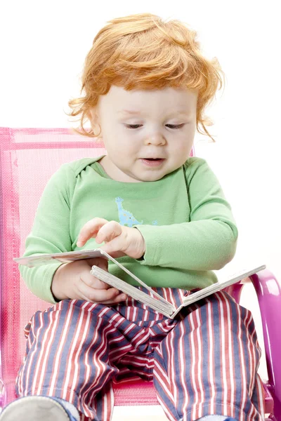 Маленький мальчик с книгой на стуле — стоковое фото