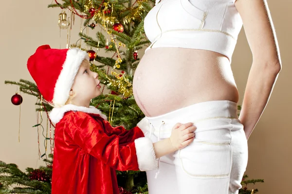 小さな女の子とクリスマス tre によって彼女の妊娠中の母親の肖像画 — ストック写真