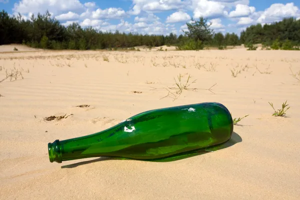 Groene fles in zand — Stockfoto