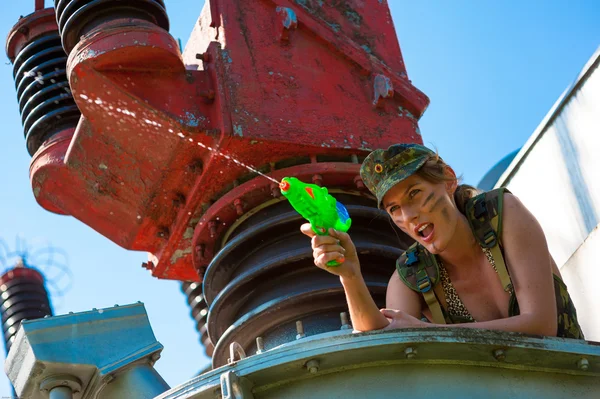 Vrouw in camouflage scheuten van een water pistool — Stockfoto