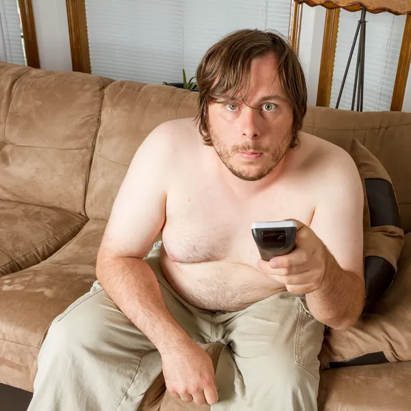 Mladý muž sedí na gauči, pracuje v televizi — Stock fotografie